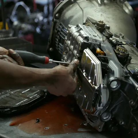 Close-up of hands working on a transmission assembly on a workbench