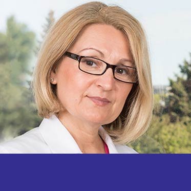 Alexandra Bialy wearing glasses and a white coat in her professional portrait