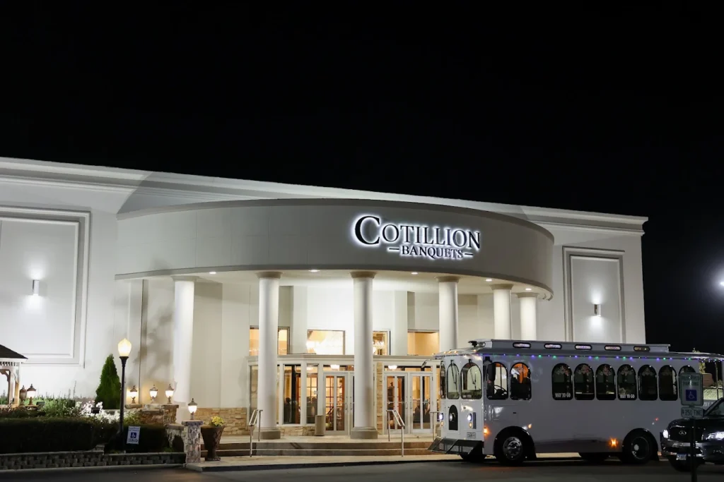 Illuminated venue entrance with a parked trolley; Cotillion Banquets gallery