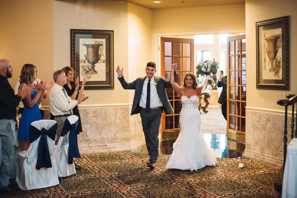Wedding couple entering the reception with guests nearby; Cotillion Banquets gallery