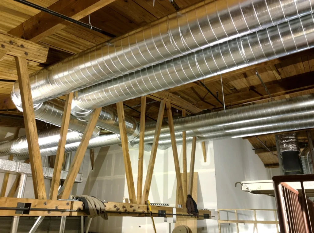 Metal ventilation ducts beneath exposed wooden framing on the Emex Company website