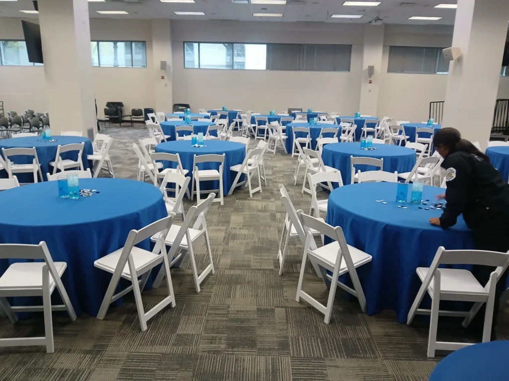 Banquet room with blue table linens and white chairs shown by Fiesta Party Rental