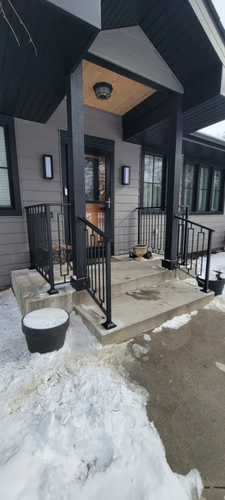 Black metal porch framing and railing beside a house in winter in the JG Welding gallery