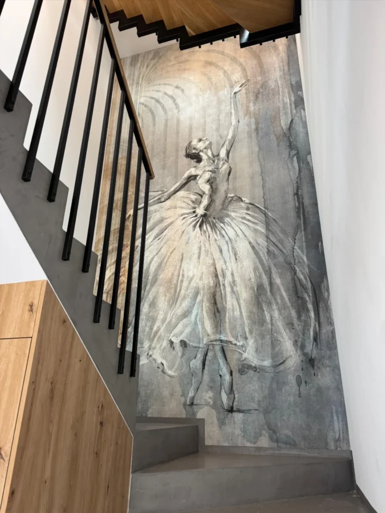 Black metal staircase railing beside a decorative wall mural in the JG Welding gallery