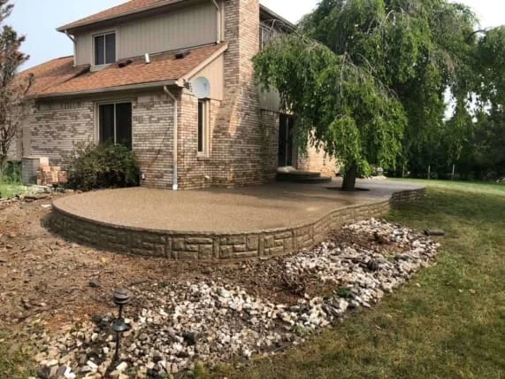Curved concrete patio with raised perimeter shown by Salor Remodeling