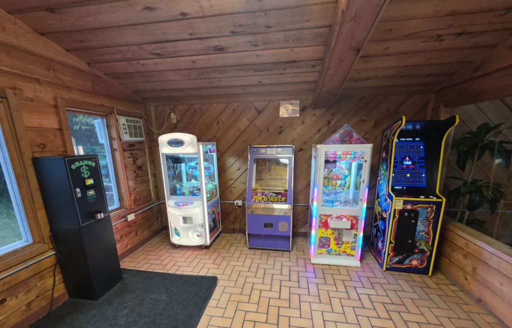 Shamrock Motel game room with claw machines and an arcade cabinet in bright lighting